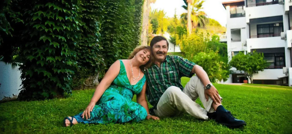 Психолог Светлана Сухова и ее муж сидят на траве, счастливо улыбаясь, что демонстрирует их гармоничные отношения.
