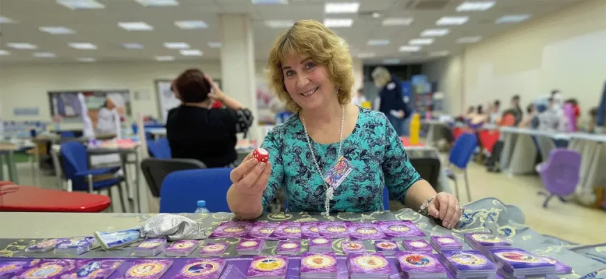 Психолог Светлана Сухова проводит трансформационную игру для отношений «Вместе нельзя расстаться», улыбаясь и держа в руке игральный кубик.